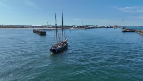 traditional tall ship entering blyth harbour with industrial area seen in the background