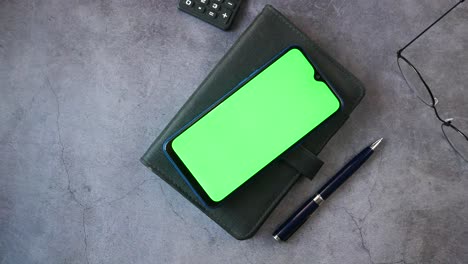 teléfono inteligente con pantalla verde en un escritorio