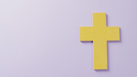 Video-of-yellow-christian-crucifix-cross-symbol-on-lilac-background-with-copy-space
