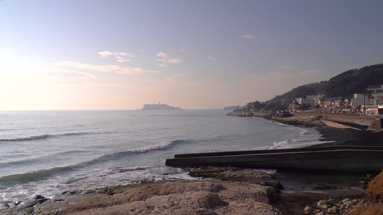 Vista fija amplia de la costa en Japón con Enoshima al fondo