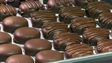 close up of chocolate piping designs being squeezed onto round chocolate sweets at a bakery