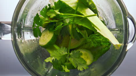 Top-view-blender-start-mixing-vegetables-herbs-in-super-slow-motion-close-up.