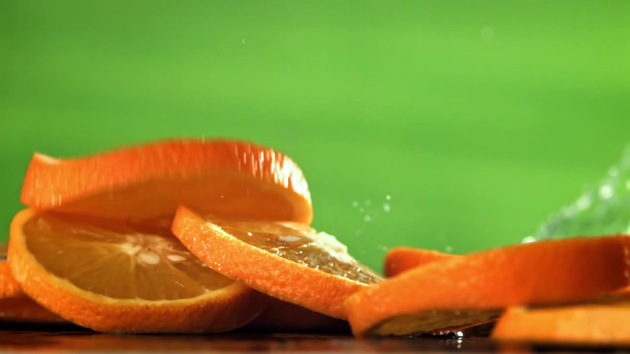Rodelas de Laranja Frescas Espirrando na Água em Câmera Lenta