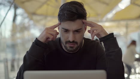 concentrated man using laptop computer in cafe