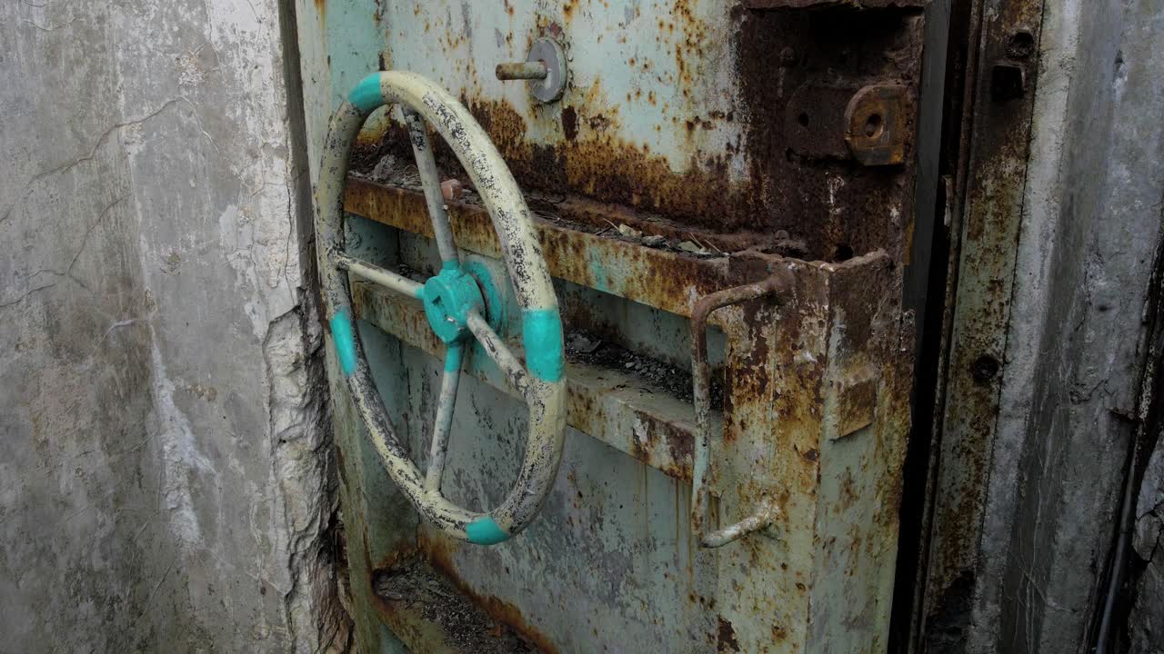 민간인을 숨기기 위해 콘크리트 폭탄 보호소 밖에 있는 오래된 강철 문, 오래된 해안 요새에 지어진 지하 종말 벙커, 중간 핸드헬드 샷