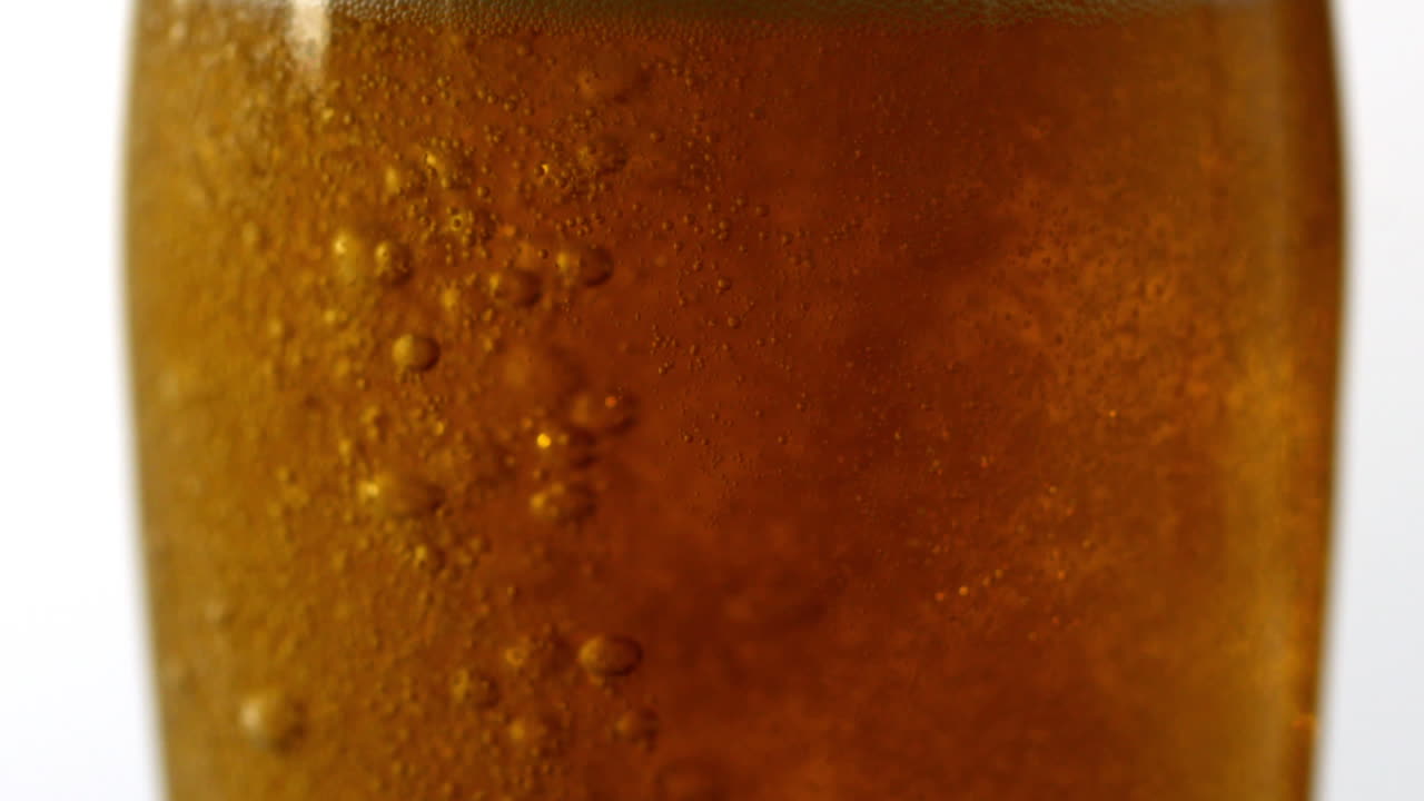 Bicchiere di birra che ribolle su sfondo bianco