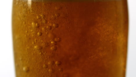 un vaso de cerveza burbujeando sobre un fondo blanco