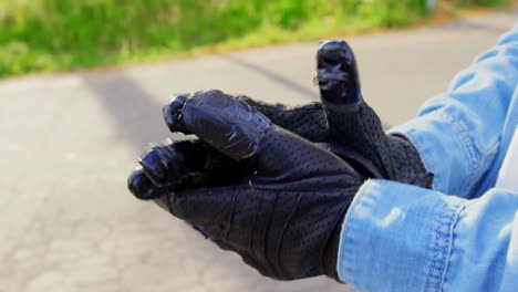 close-up of young male skateboarder checking skateboard gloves in the sunshine 4k