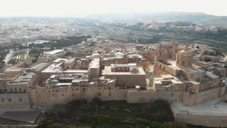 mdina, the silent city, view outside city walls overlooking the cityscape limestone buildings in malta - ascending panoramic aerial shot