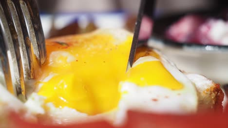 cutting into a runny fried egg on toast
