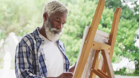 Video-of-african-american-senior-man-painting-picture-outside
