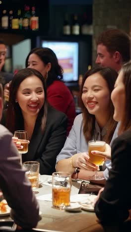 diverse group of work colleagues out for drinks chatting and laughing.