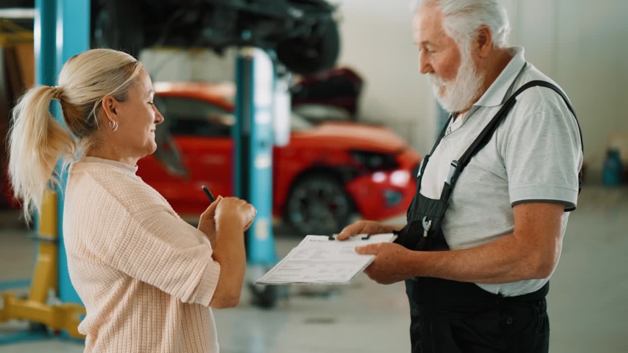 fotografía media de un cliente femenino firmando un documento con un mecánico automotriz después de dejar su coche para reparaciones