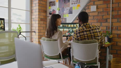 graphic designers working on photos over computer at desk in office 4k