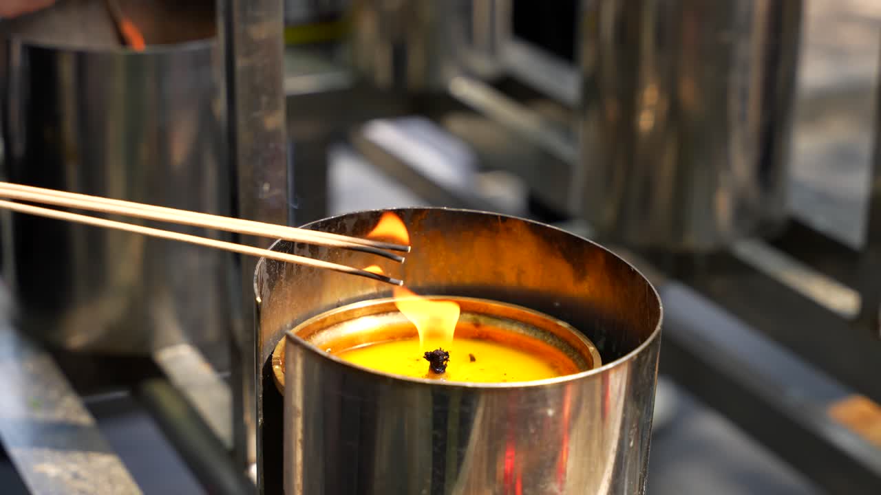 Røgelsespinde brændes i en stearinlysflamme under et bønneritual i Lama-templet i Beijing