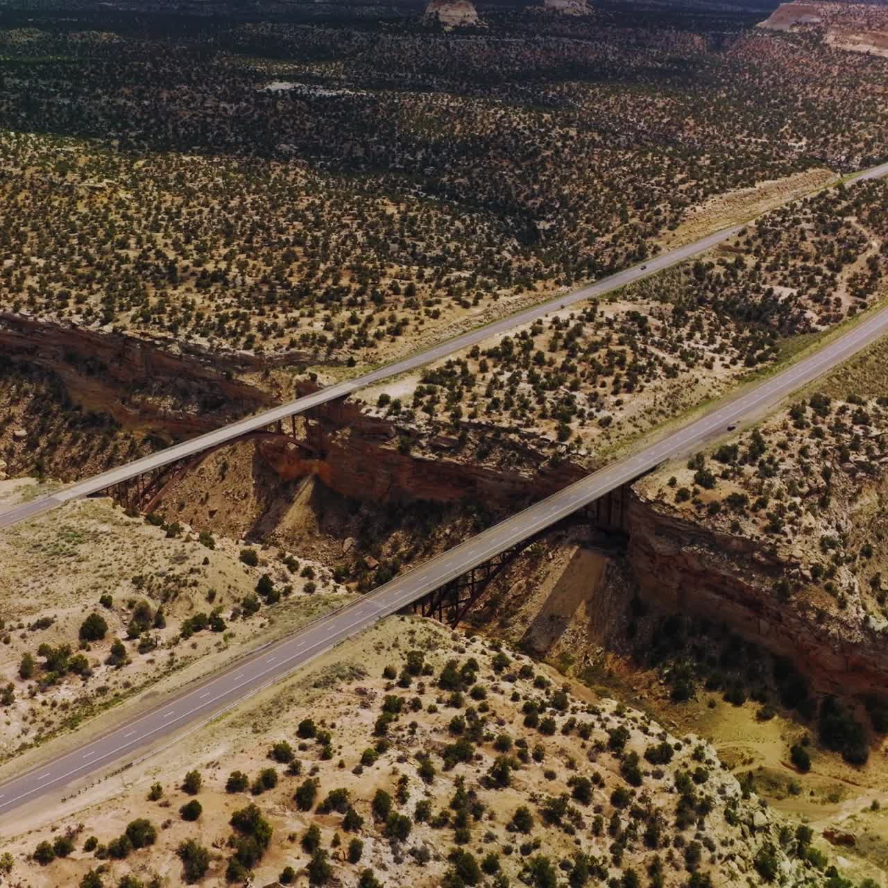Huge crack in the rocks of desert in Utah, USA. Bridges connecting the sides of a split for transport to pass. Aerial view