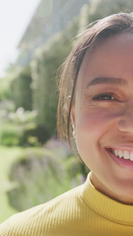 vertical video of portrait of biracial woman looking at camera and smiling, in slow motion