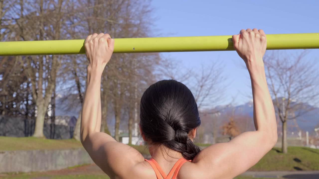 detrás de la vista de una mujer deportiva haciendo pullups, primer plano