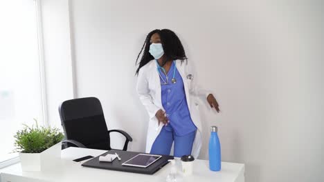 Black-female-doctor-in-medical-mask-dancing-in-clinic