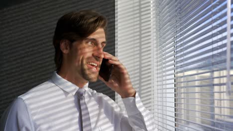 Front-view-of-young-Caucasian-male-executive-talking-on-mobile-phone-in-a-modern-office-4k