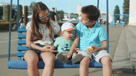 adorable brothers and sister in amusement park. cute siblings riding on swing