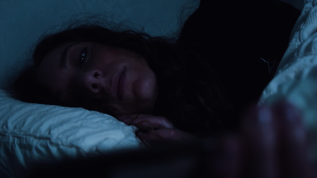 mujer se acuesta en la cama mientras usa su teléfono inteligente tarde en la noche