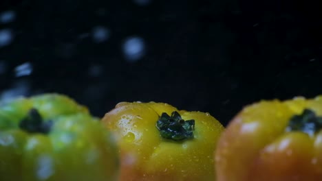 Wasser-Spritzt-über-Drei-Große-Gelbe-Fleischtomaten-Mit-Schwarzem-Hintergrund