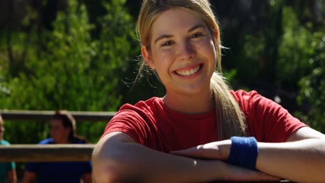 portrait of female trainer leaning on wooden frame during obstacle course