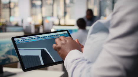 close up of technician using tablet to create solar powered device design