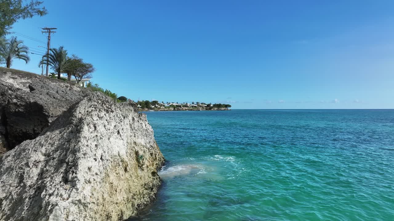 Turquoise Caribbean water meeting rocky cliffs and palm trees on Barbados coastline