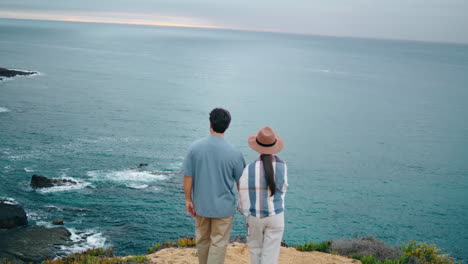 romantic couple walking sea shore back view. pair looking on picturesque ocean.