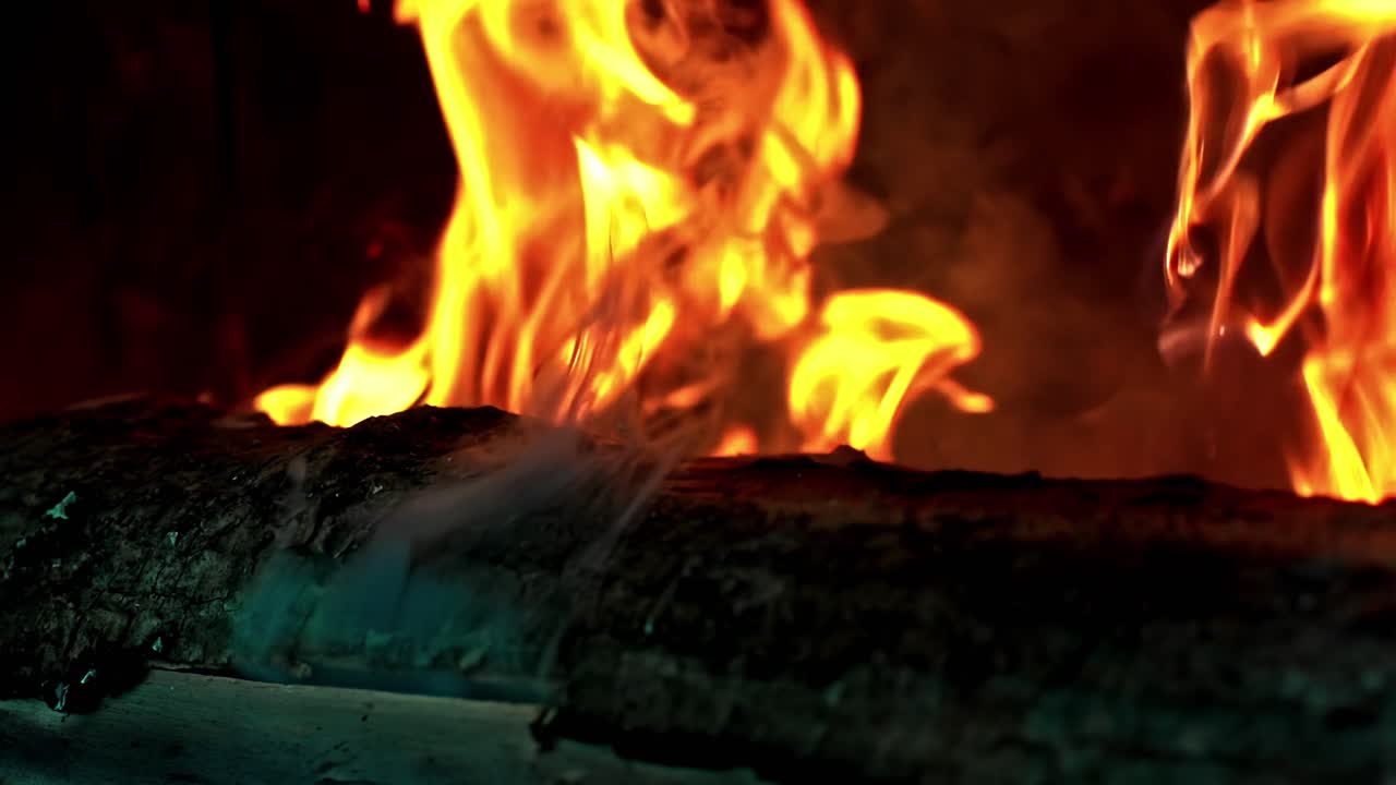 Burning wooden log in indoor fireplace with bright orange flames producing warmth, light, and cozy atmosphere