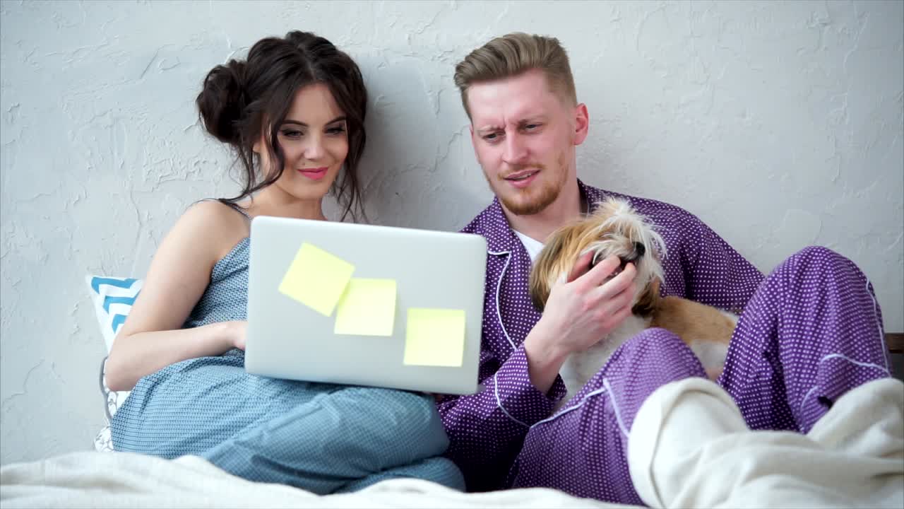 Couple Watching Laptop with Dog in Pajamas