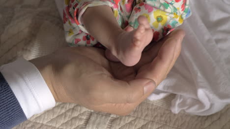 los pies del bebé en la mano de papá