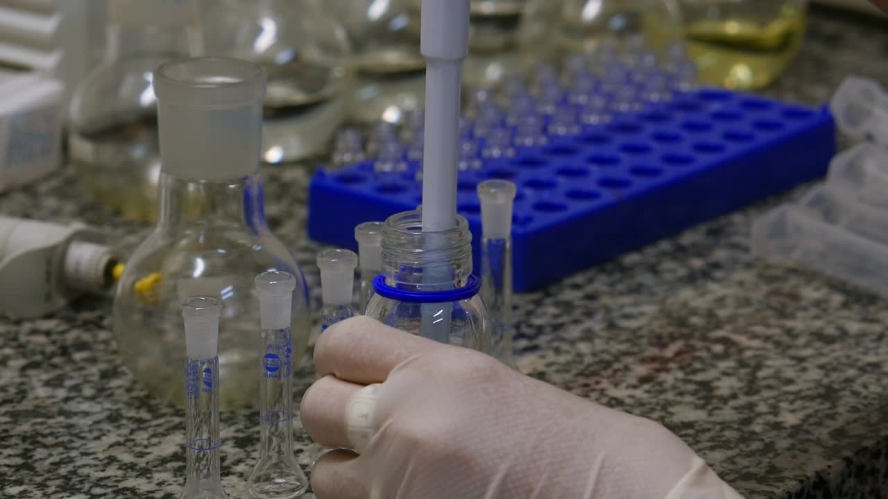 A scientist's hand handling an automatic pipette to measure and transfer liquid samples