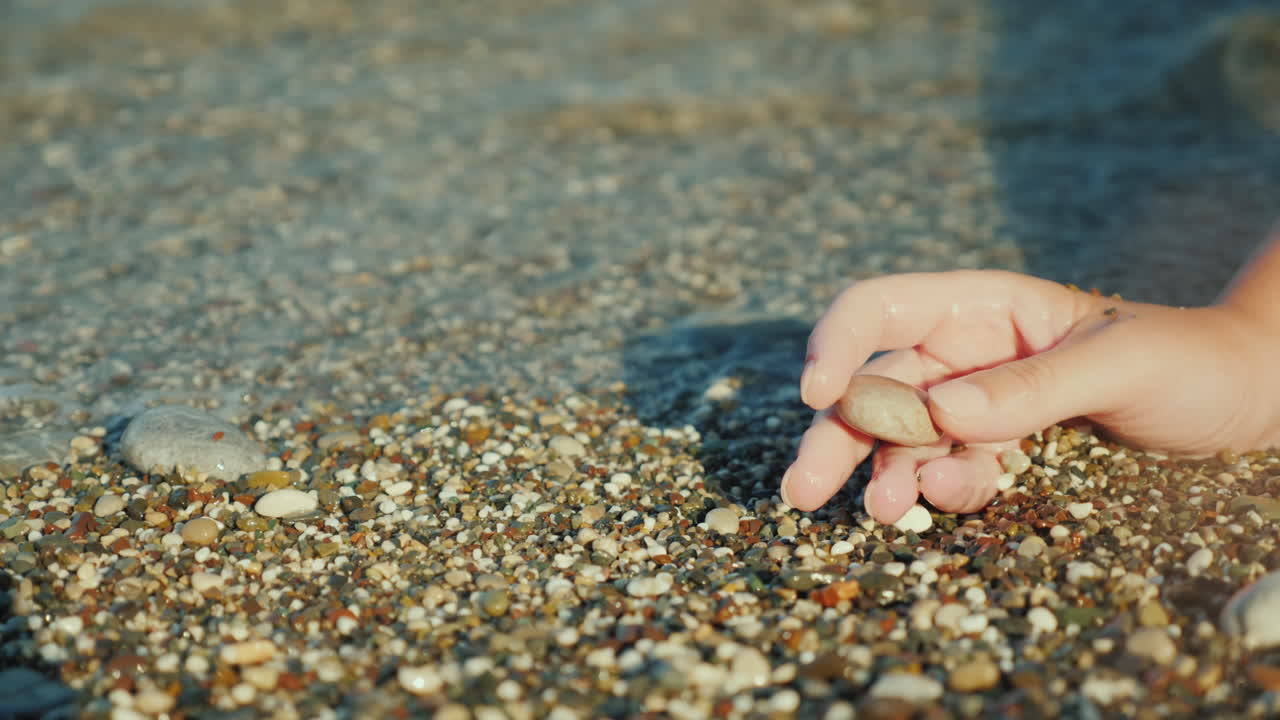 한 여자의 손이 서핑 4k 비디오의 배경에 조약돌을 들고 있다