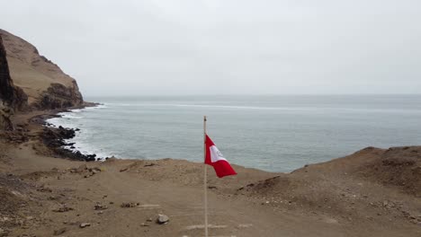 drone video of a peruvian flag post near a cliff edge on ocean coast