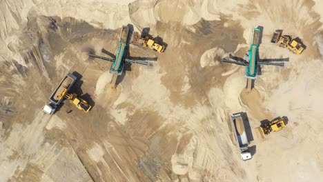 Aerial-view,-machinery-working-at-clay-quarry,-heavy-loaders,-large-trucks,-bulldozers,-excavators,-Sand-quarry,-Mining,-Truck-takes-raw-materials-from-the-quarry,-Large-clay-warehouse