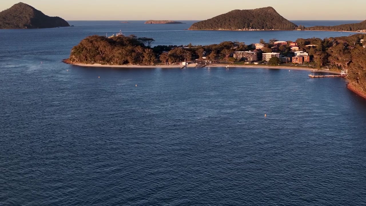 Vista aérea ampla da costa e colinas de Nelson Bay durante a hora dourada na Austrália.