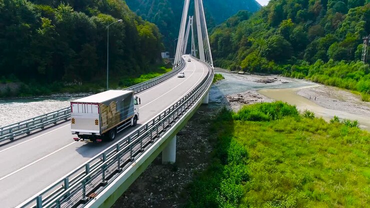Truck Crossing a Bridge Over a River in a Mountainous Area
