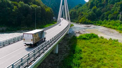 truck crossing a bridge over a river in a mountainous area