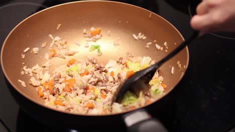 stirring and frying rice with vegetables in a pan