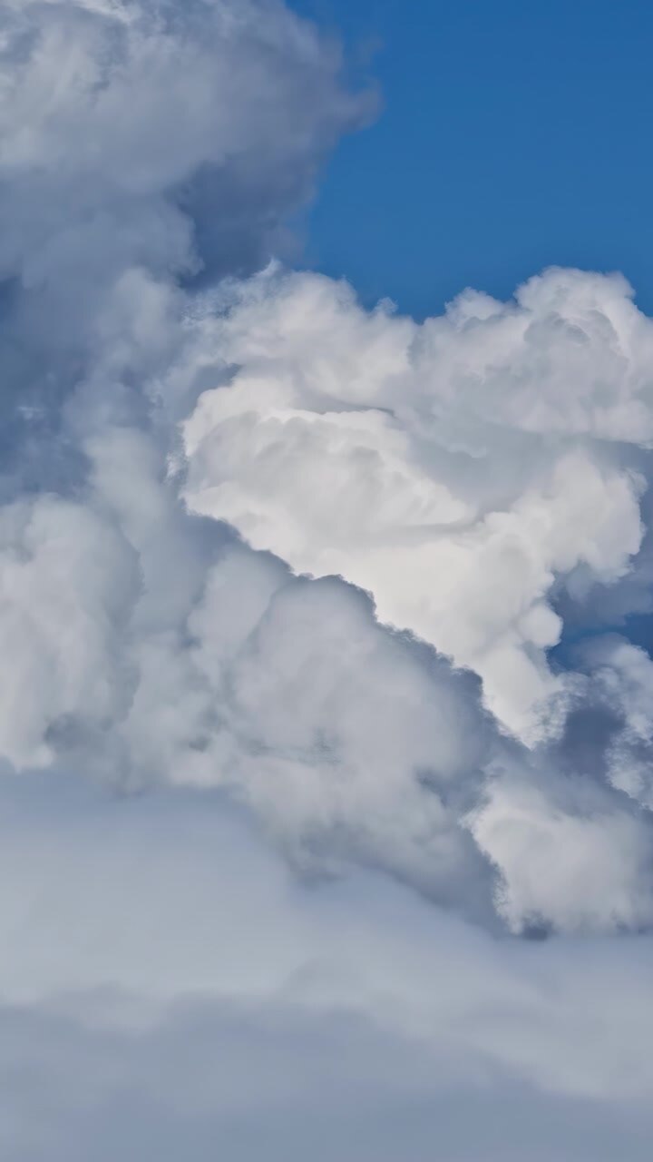 Vertical aerial pan left capturing dramatic clouds surrounding a telecommunications tower during early morning conditions.