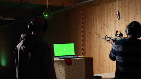 mockup laptop and shooting gallery safety officer watching client shoot targets