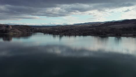 dramatic aerial shot over the lake surface establishing the view of the rigid romanian panorama at winter