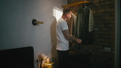 hombre vaporizando ropa en su dormitorio