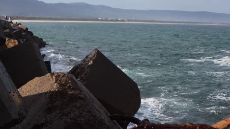 las grandes olas chocan contra los bloqueadores de olas de piedra en la costa