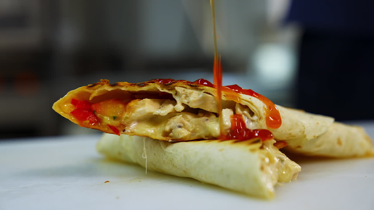 Tasty pita roll with vegetables and meat poured with red souce. Tasty fast food prepared in restaurant.