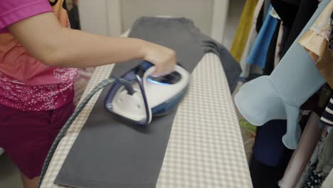 closeup of a woman ironing clothing by stream iron on board at home