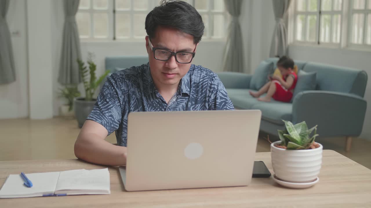 Asian Man Working With Laptop Computer And Son Use Mobile Phone , Video In 4K